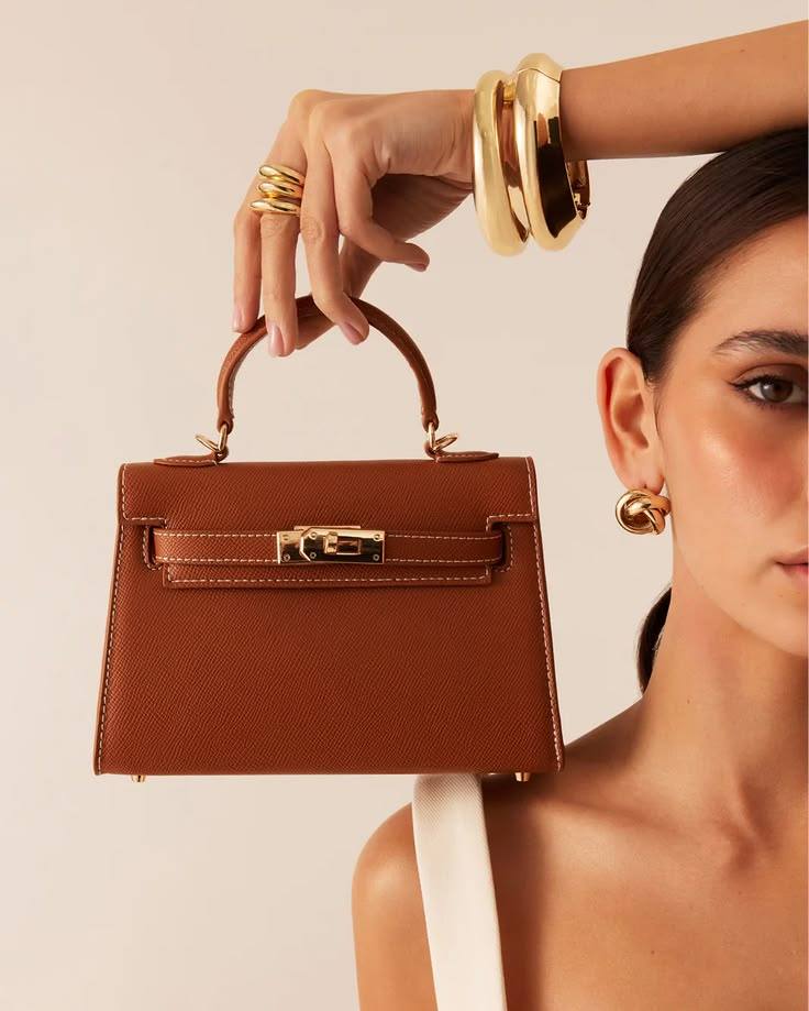 Modelo segurando uma bolsa de couro caramelo
